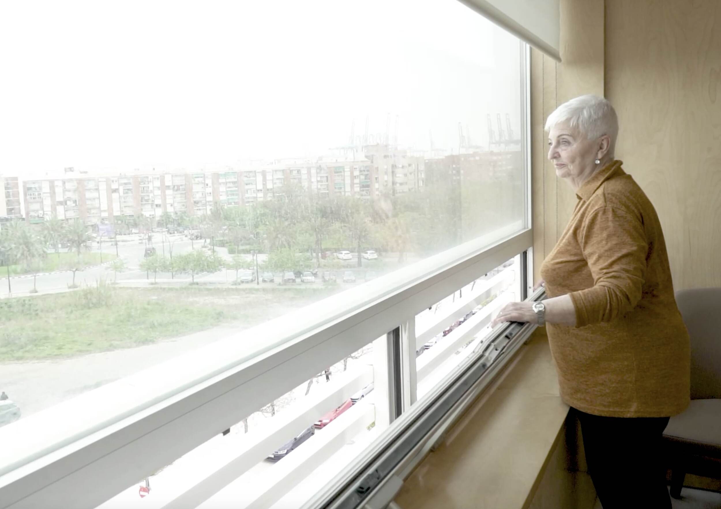 Maria Angeles intervenida de rodilla mirando por la ventana