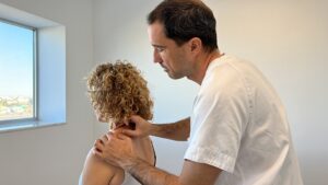 paciente recibiendo masaje en el trapecio. fisioterapia. Hospital Ribera IMSKE es un hospital de traumatología y rehabilitación situado en Valencia. Es una institución médica líder en la prevención, el diagnóstico y el tratamiento de enfermedades musculoesqueléticas. Avalado por un equipo multidisciplinar de más de 100 profesionales altamente cualificados y especializados, Ribera IMSKE consolida su posición como centro de excelencia en el sector de la medicina y ofrece al paciente la cobertura de todas las especialidades musculoesqueléticas. La traumatología y la rehabilitación eso nuestras pasiones, y el compromiso y el cuidado sin límites con el paciente, nuestra prioridad.